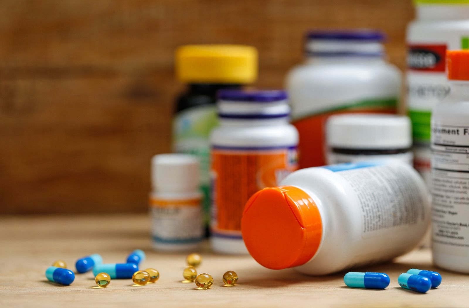 Supplement bottles and capsules on a wooden desk